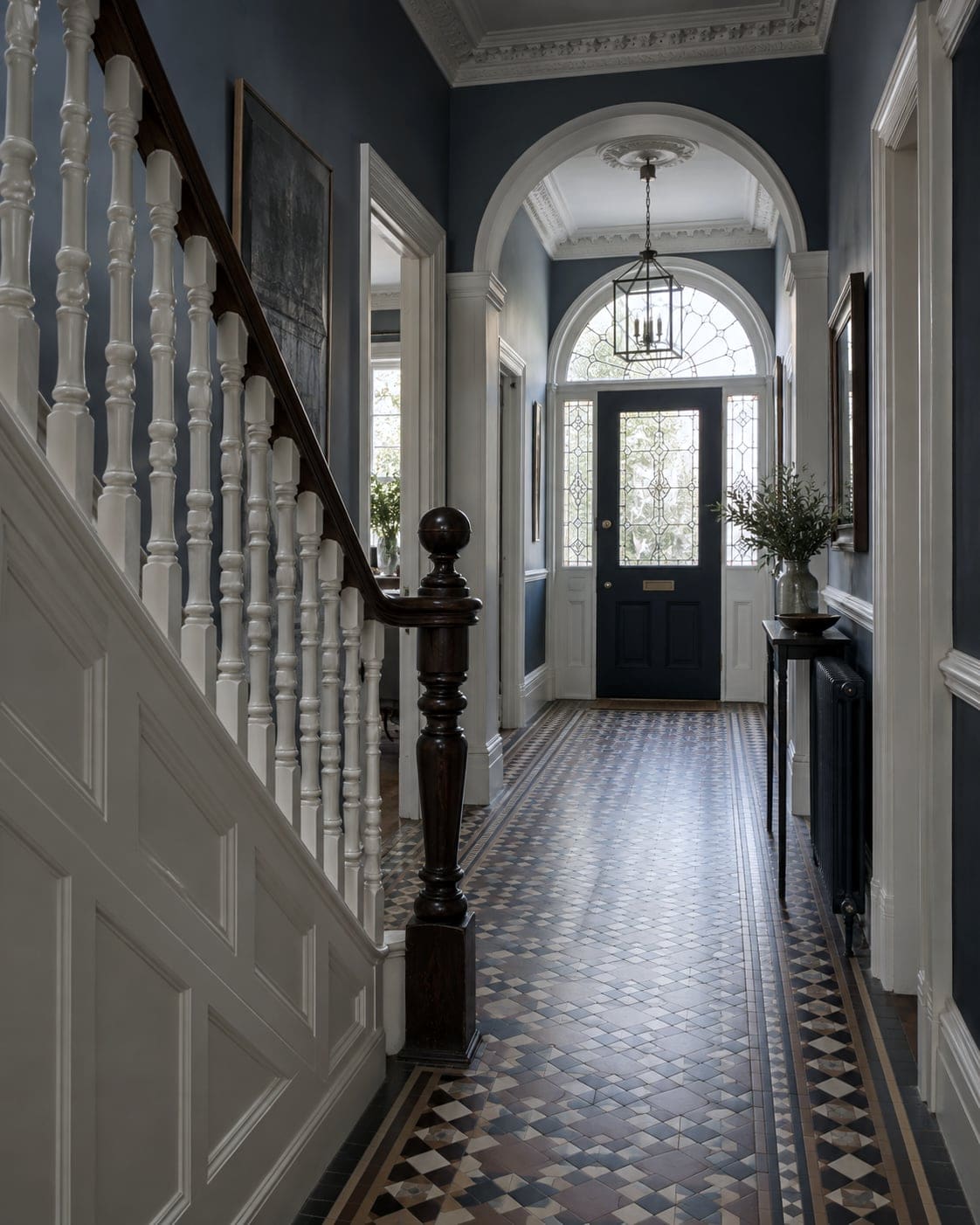 Restored Victorian hallway with painted staircase and encaustic tiled floor